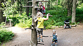 Kinder klettern an einem Kletterbaum im Wald.