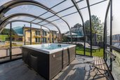 Überdachter Outdoor-Whirlpool im Glas-Pavillon mit Blick auf Garten und Gebäude des Hotel Engel im Schwarzwald