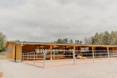 Großzügige Reithalle mit Außenbereich und Pferden beim Familienhotel Friedrichshof.