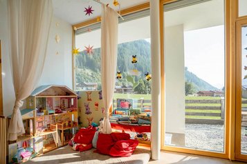 Happy-Club im Alpenhotel Kindl mit Puppenhaus, Bücherecke und großen Fenstern mit Blick auf die Berge.