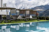 oolbereich mit modernen Daybeds und Sonnenschirmen im Familienhotel Almfamilyhotel Scherer vor beeindruckender Bergkulisse.