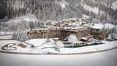 Winterliche Visualisierung des Familienhotels Alpura Retreat in Südtirol mit verschneiter Bergkulisse, Chalets und Außenanlagen.
