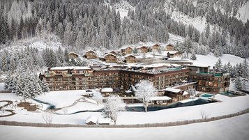Winterliche Visualisierung des Familienhotels Alpura Retreat in Südtirol mit verschneiter Bergkulisse, Chalets und Außenanlagen.