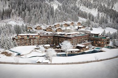 Winterliche Visualisierung des Familienhotels Alpura Retreat in Südtirol mit verschneiter Bergkulisse, Chalets und Außenanlagen.