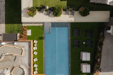 Draufsicht auf den Outdoor-Pool und die Liegewiese des Familienhotels Scherer mit stilvoller Gartenanlage.