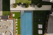 Draufsicht auf den Outdoor-Pool und die Liegewiese des Familienhotels Scherer mit stilvoller Gartenanlage.