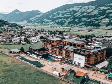 Das Familienhotel Mia Alpina in Tirol von oben mit Poolbereich, Liegewiese und Bergpanorama.