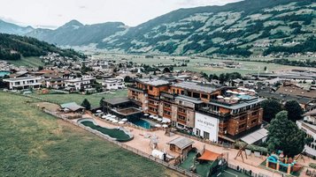 Das Familienhotel Mia Alpina in Tirol von oben mit Poolbereich, Liegewiese und Bergpanorama.