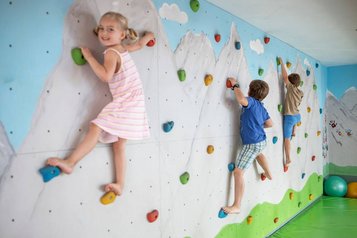 Drei Kinder klettern an der Kletterwand des Familienhotels Kaiserhof an der Zugspitze.