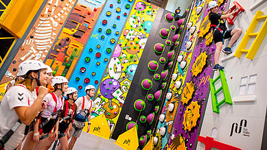 Teens stehen vor einer großen Boulderwand im Familienhotel Kolping Hotel Spa & Family Resort in Ungarn.