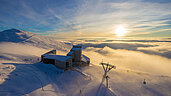 Eine Luftaufnahme von dem Skipanorama Bad Kleinkirchheim im Winter. Die Sonne strahl in der Ferne und zeigt Kaernten von der besten Seite. K