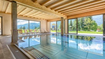 Lichtdurchfluteter Indoorpool mit traumhaftem Bergblick im Familienhotel Ramsi in Kärnten