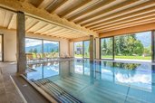 Lichtdurchfluteter Indoorpool mit traumhaftem Bergblick im Familienhotel Ramsi in Kärnten