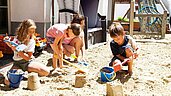 Kinder spielen im Sandkasten und bauen Sandburgen im Adler Familien- & Wohlfühlhotel in Tirol.