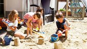 Kinder spielen im Sandkasten und bauen Sandburgen im Adler Familien- & Wohlfühlhotel in Tirol.