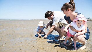 Familie mit Kleinkindern sucht Muscheln am Nordseestrand im Familienurlaub an der Nordsee.