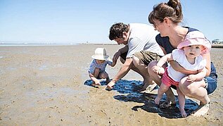 Familie mit Kleinkindern sucht Muscheln am Nordseestrand im Familienurlaub an der Nordsee.
