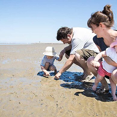 Familie mit Kleinkindern sucht Muscheln am Nordseestrand im Familienurlaub an der Nordsee.