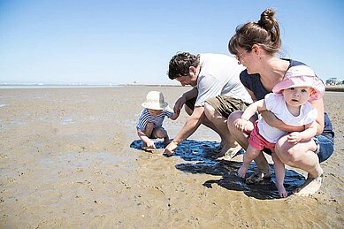 Familie mit Kleinkindern sucht Muscheln am Nordseestrand im Familienurlaub an der Nordsee.