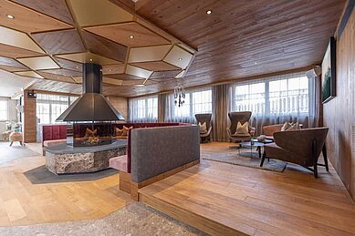 Große Lobby mit vielen Sitzmöglichkeiten und einem Kamin im Familienhotel Galtenberg Family & Wellness Resort in Tirol.