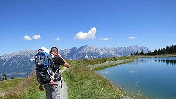 Vater mit Baby in der Kraxe beim Wandern in Deutschland.