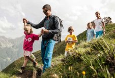 Familie mit Baby wandert durch die schöne Landschaft im Familienurlaub in Tirol.