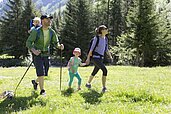 Familie mit Baby wandert durch die schöne Landschaft im Familienurlaub in Tirol.