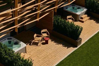 Terrasse im Familienhotel Bella Vista in Südtirol mit Whirlpool, Liegen, Holzboden und privatem Gartenbereich.