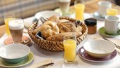Gedeckter Tisch zum Frühstück mit Semmeln, Orangensaft und vielem mehr im Kinderhotel Bruckwirt in Oberösterreich.