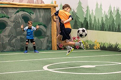 Zwei Jungs spielen Fußball auf dem Indoor Fußballplatz des Familienhotels Sonnenpark im Sauerland.