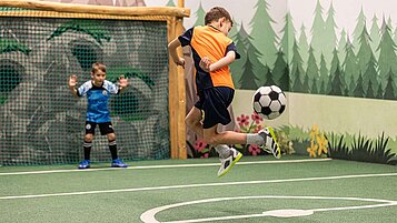 Zwei Jungs spielen Fußball auf dem Indoor Fußballplatz des Familienhotels Sonnenpark im Sauerland.