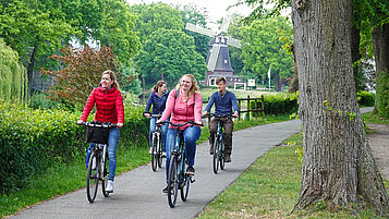 Eine Familie fährt mit dem Fahrrad über den Stadtwall in Meppen auf einem Kiesweg.