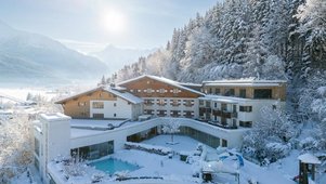 Winterliche Außenansicht mit Pool und verschneiter Berglandschaft beim Familienhotel Amiamo im Salzburger Land.