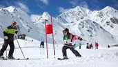 Kind fährt beim Skirennen durch einen Slalomkurs im Gäste-Winterprogramm des Hotels Bella Vista in Südtirol, im Hintergrund schneebedeckte Berge.