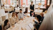 Eine Familie sitzt gemeinsam im Restaurant des Hotel Sonngastein im Salzburger Land am gedeckten Tisch.