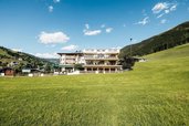 Außenansicht des Wellness- & Familienhotels Egger mit großer Wiese und Bergkulisse im Salzburger Land.