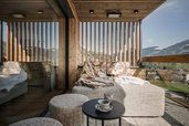 Eine helle Suite im Familienhotel Mia Alpina in Tirol mit gemütlicher Sitzecke auf dem Balkon, großen Fenstern und Panoramablick auf die Berge.
