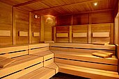 Gemütliche Saunalandschaft im Hotel Sonnenhügel mit mehrstufigen Holzbänken und sanfter Beleuchtung für ein entspannendes Wellness-Erlebnis.