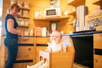 Mutter und Kind sind in der Babyecke und bedienen sich am Babybuffet des Familienhotels Landhau szur Ohe im Bayerischen Wald.
