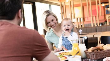 Eine Familie genießt ein entspanntes Frühstück im Familienhotel – frische Brötchen, gesunde Säfte und glückliche Momente für Groß und Klein