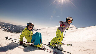 Zwei Kinder auf Skiern auf der Skipiste.