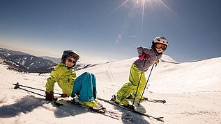 Zwei Kinder auf Skiern auf der Skipiste.