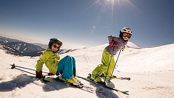 Zwei Kinder auf Skiern auf der Skipiste.