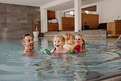 Eine glückliche Familie die im Indoor-Pool plantscht. 