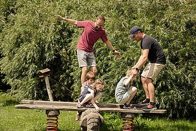 Eltern spielen mit Ihren Kinder auf dem Spielplatz des Familien Wellness Hotel Seeklause an der Ostsee.