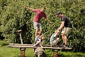 Eltern spielen mit Ihren Kinder auf dem Spielplatz des Familien Wellness Hotel Seeklause an der Ostsee.