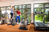 Ein Man und eine Frau trainieren gemeinsam im Fitnessraum des Familienhotels Sonngastein in Bad Gastein.