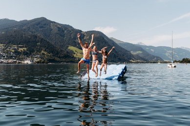 Familie springt gemeinsam in den See am Badeplatz im Familienhotel Amiamo im Salzburger Land.
