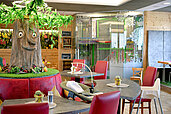 Das bunte und liebevoll gestaltete Familienrestaurant im Familienhotel Rhön Feeling. In der Mitte des Restaurants befindet sich ein Baum, auf dem ein lachendes Gesicht dargestellt ist.