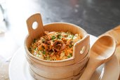 Traditionelle Kässpätzle mit Röstzwiebeln im Holzschälchen serviert im Familienhotel Sonne Bezau.